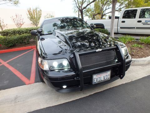 2003 Ford Crown Victoria - Black Ford Crown Victoria parked in a lot, brush guard and California EVIL VIC plate visible up front.