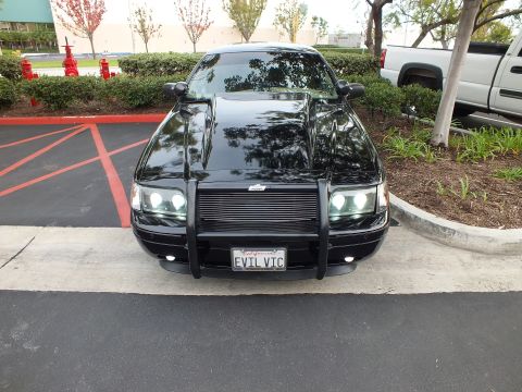 2003 Ford Crown Victoria - Straight-on front shot of a black Crown Victoria showing symmetrical billet grille, brush guard and plate.