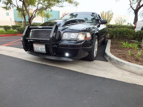 2003 Ford Crown Victoria - Low front angle of a black Crown Victoria with halo projector lights, grille guard and EVL VIC plate.