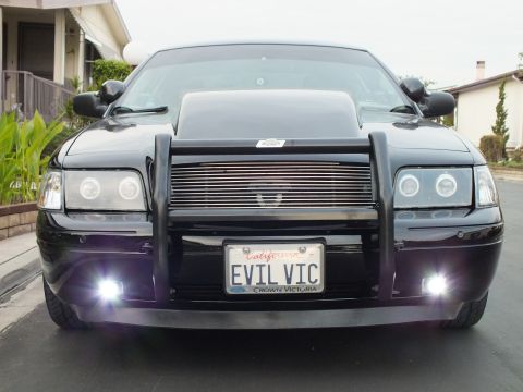 2003 Ford Crown Victoria - Front view of a black Crown Victoria with glowing halo headlights and white fog lamps, EVIL VIC plate centered.
