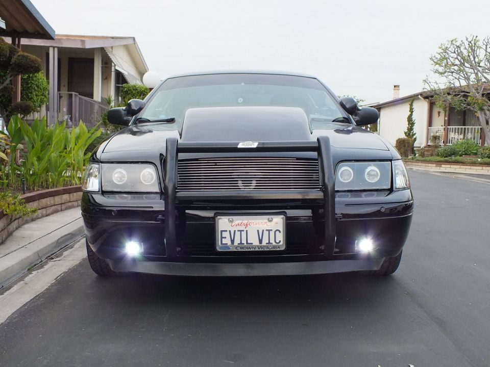 Black Crown Victoria head-on on residential street with halo headlights and EVIL VIC plate