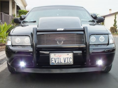 2003 Ford Crown Victoria - Close front view of a black Crown Victoria with chrome billet grille, halo headlights and lit fog lamps.