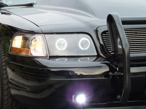 2003 Ford Crown Victoria - Tight detail of a black Crown Victoria left corner showing dual halo projector lights and a bright fog lamp.