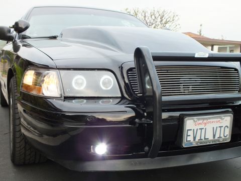 2003 Ford Crown Victoria - Three-quarter front view of a black Crown Victoria with halo headlights, hood scoop and EVIL VIC California plate.