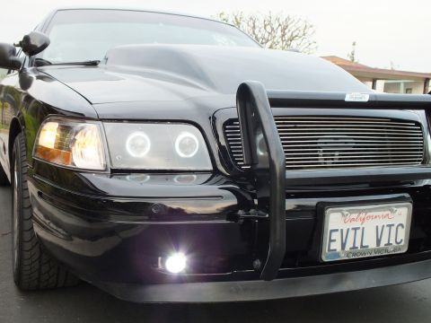 2003 Ford Crown Victoria - Front angle of a customized Crown Victoria with chrome billet grille, push bar and lit fog lamp.