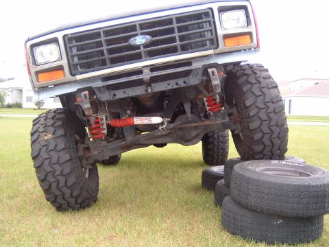 1983 Ford Bronco - Front view of a 1983 Ford Bronco, modified with large off-road tires and visible red suspension components.
