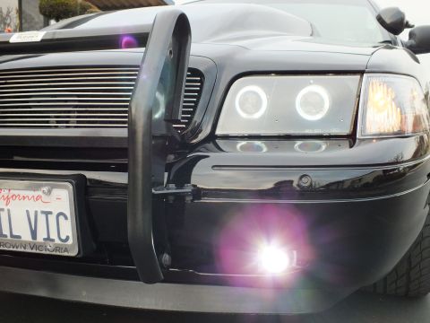 2003 Ford Crown Victoria - Glowing halo rings and a bright LED fog light flank the billet grille of a black Crown Victoria.