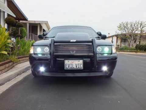 2003 Ford Crown Victoria - Black Crown Victoria photographed head-on showing halo headlights, push bar and chrome billet grille.