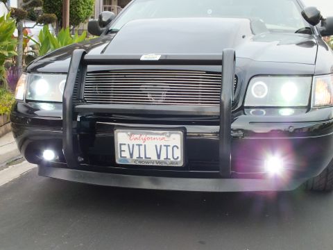2003 Ford Crown Victoria - Close front view of a Crown Victoria with hood scoop, chrome billet grille and lit halo headlights.