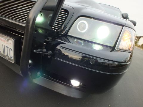 2003 Ford Crown Victoria - Tight corner view of a Crown Victoria's halo projector headlight, billet grille and black push bar.
