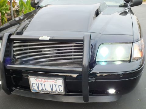 2003 Ford Crown Victoria - Front view of a Crown Victoria showing the hood scoop, chrome billet grille and lit dual headlights.