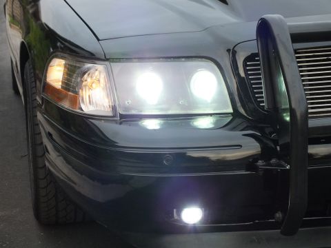2003 Ford Crown Victoria - Close front-corner view of a Crown Victoria with lit headlights, fog lamp and chrome billet grille.