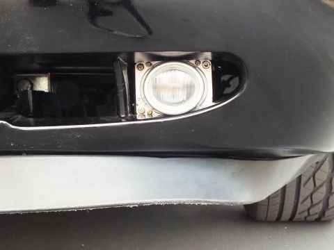 2003 Ford Crown Victoria - Detail of a chrome-bezel fog lamp set into the lower bumper of a black car.