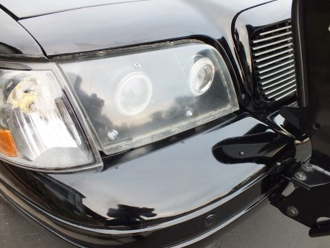 2003 Ford Crown Victoria - Headlight halo rings beside a billet grille and the black bumper guard bracket.