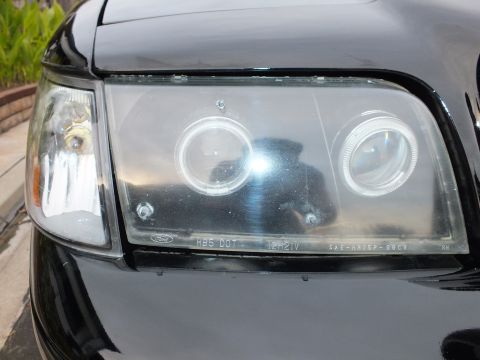 2003 Ford Crown Victoria - Detailed headlight shot showing dual halo rings and embossed lens text.