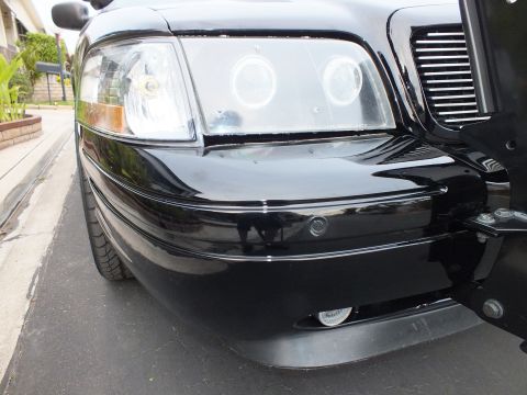 2003 Ford Crown Victoria - Front quarter detail of a black Crown Victoria with halo lights and a chrome grille.