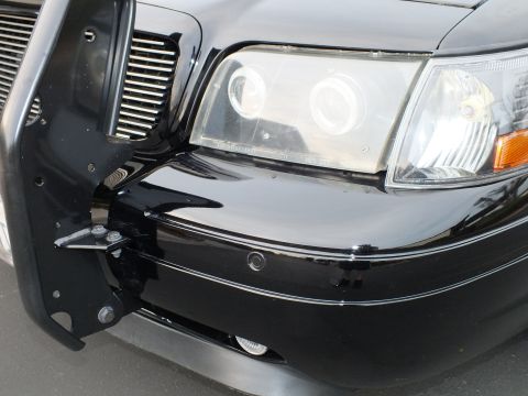 2003 Ford Crown Victoria - Angled view of the halo headlight, black bumper and grille guard mounting bracket.