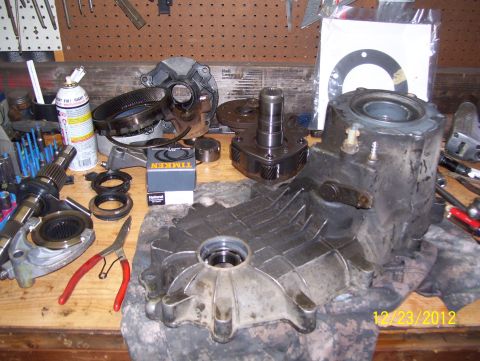 1990 Ford Bronco - Various parts of a disassembled transfer case are laid out on a wooden surface with tools.
