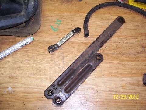 1990 Ford Bronco - Close-up of a metal bracket, hose, and ratchet tool on a wooden workbench.