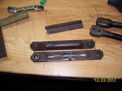 1990 Ford Bronco - Metal parts and tools are laid out on a wooden surface, possibly for repair or fabrication.