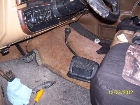 1990 Ford Bronco - The interior of a vehicle is shown, focusing on the driver's side floor area with a floor-mounted shifter and pedals.