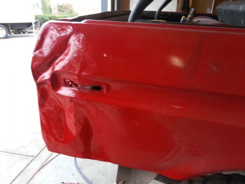 1978 Ford Bronco - The rear quarter panel of a red vehicle shows significant damage and is freshly painted.