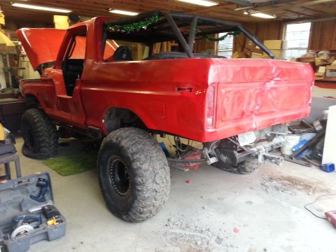1978 Ford Bronco - This red 1978 Ford Bronco, modified for off-road use with oversized tires and a roll cage, is seen in a workshop.