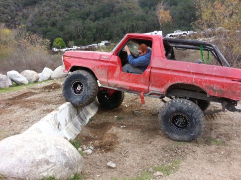 1978 Ford Bronco - Modified 1978 Ford Bronco tackling a challenging off-road course with a driver inside.