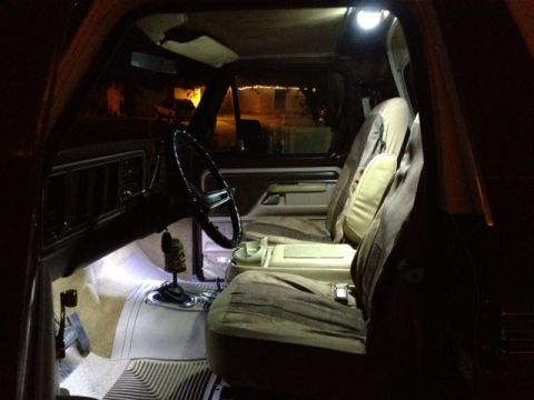 1979 Ford Bronco - The interior of the vehicle is illuminated by aftermarket lighting, highlighting the seats and dashboard.