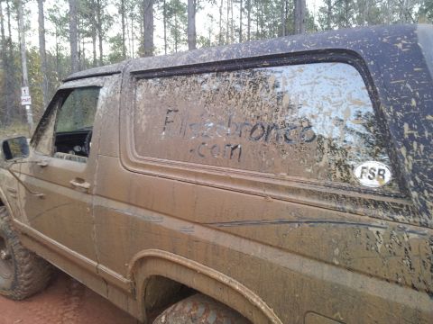1986 Ford Bronco - This muddy SUV has 'Flsdbronco.com' written on its window, suggesting it may be a Bronco.