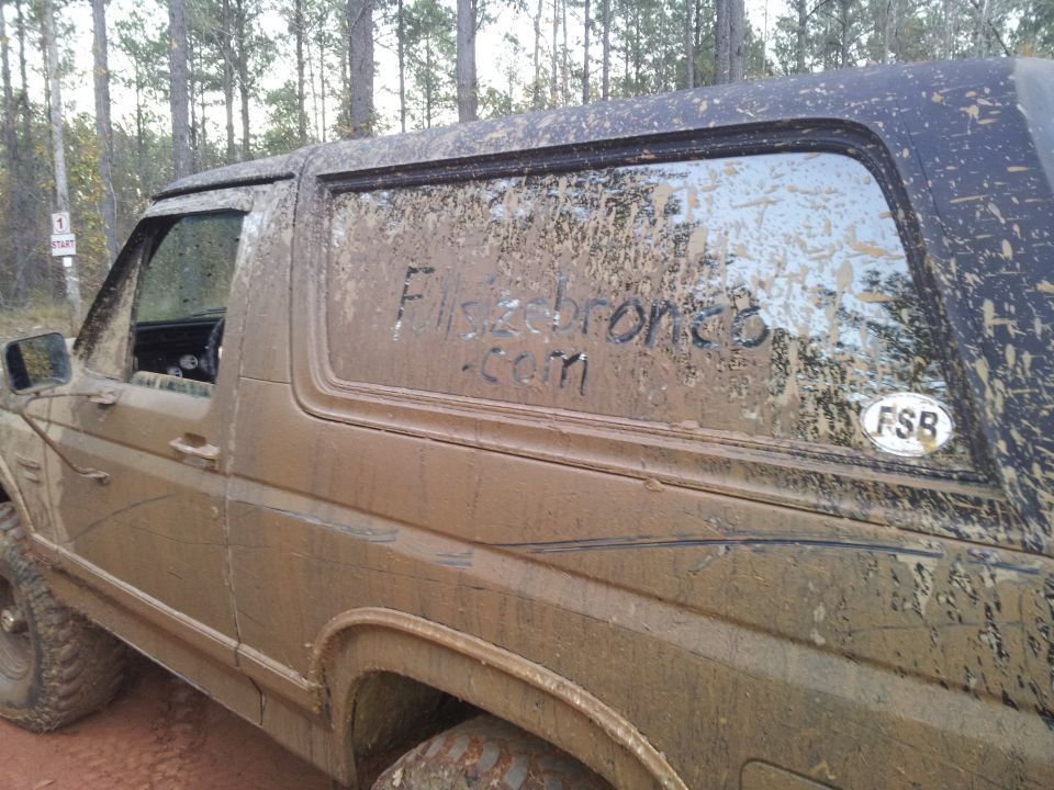 Mud-covered SUV side view with 'Flsdbronco.com' written on window