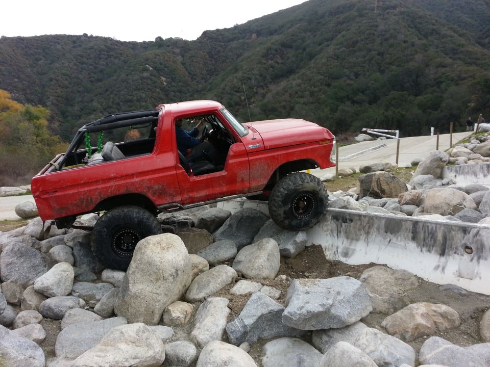 Red 1978 Ford Bronco navigating a rocky obstacle course