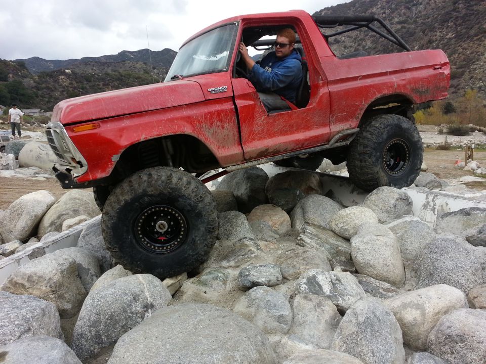 Red 1978 Ford Bronco climbing over rocks