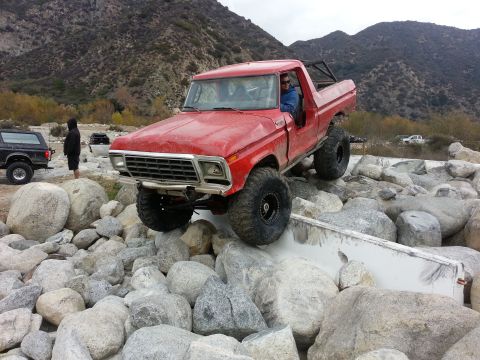 1978 Ford Bronco - A red 1978 Ford Bronco navigates a rocky obstacle course in a canyon.