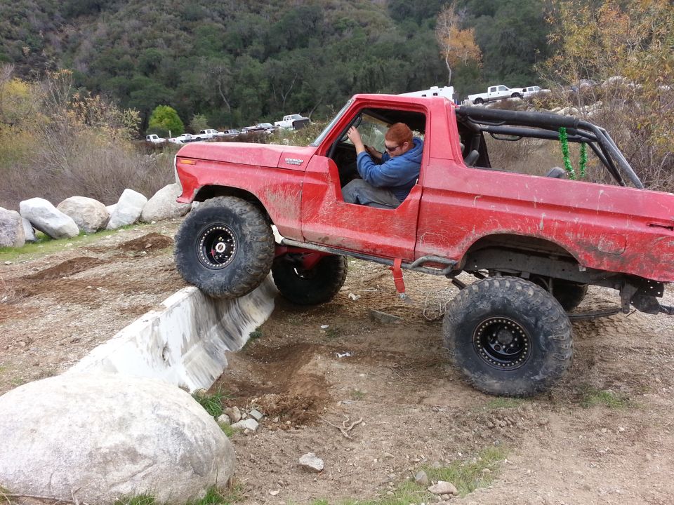 Red 1978 Ford Bronco with large tires on a rocky trail