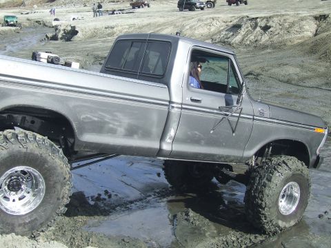 1978 Ford Bronco - A modified pickup truck navigates a muddy terrain with other vehicles visible in the background.