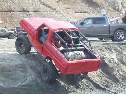 1978 Ford Bronco - Modified 1978 Ford Bronco tackling a steep dirt incline with a roll cage installed for safety.