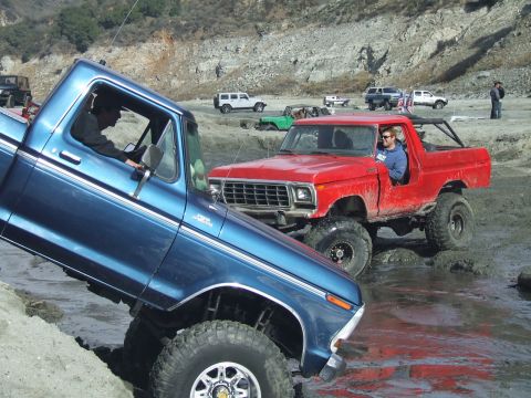 1978 Ford Bronco - A red 1978 Ford Bronco navigates a muddy terrain alongside another off-road vehicle.