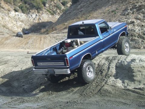 1978 Ford Bronco - A blue pickup truck navigates a sandy incline during an off-road excursion.