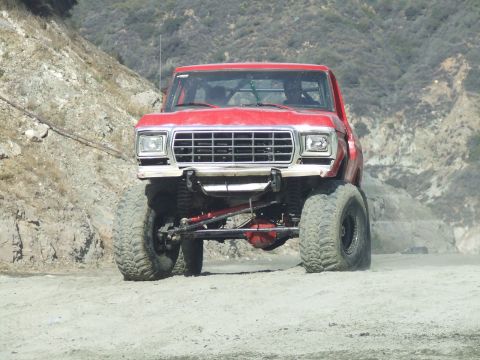 1978 Ford Bronco - A red 1978 Ford Bronco modified for off-road use navigates a dusty trail.