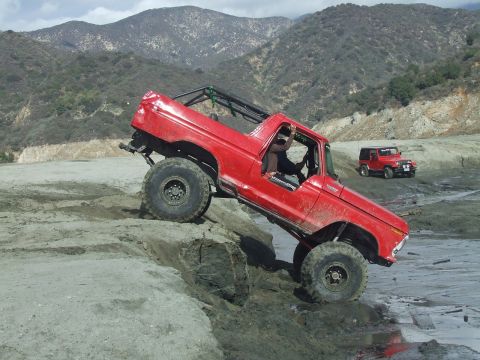 1978 Ford Bronco - 1978 Ford Bronco tackling a challenging off-road trail with a Jeep in the distance.