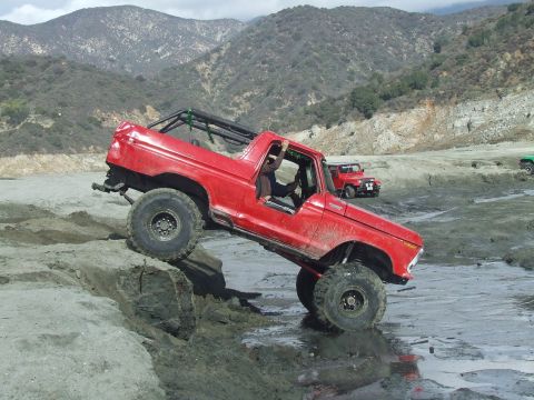 1978 Ford Bronco - This red 1978 Ford Bronco is navigating a challenging off-road course with a second vehicle visible in the background.