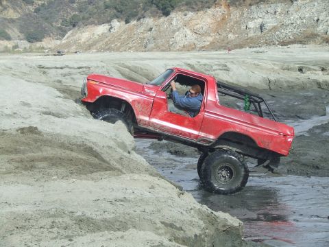 1978 Ford Bronco - This red 1978 Ford Bronco is navigating a challenging sandy terrain.