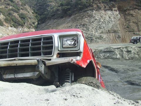 1978 Ford Bronco - A red 1979 Ford F-Series truck is stuck in the dirt, with another vehicle visible in the background.