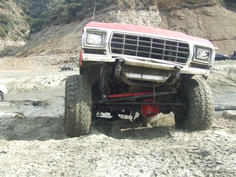 1978 Ford Bronco - Modified 1978 Ford Bronco navigating a dirt and sand trail with large tires.
