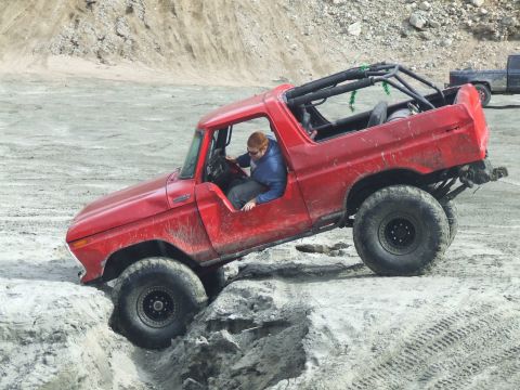 1978 Ford Bronco - This red 1978 Ford Bronco is shown off-roading through a challenging dirt track.