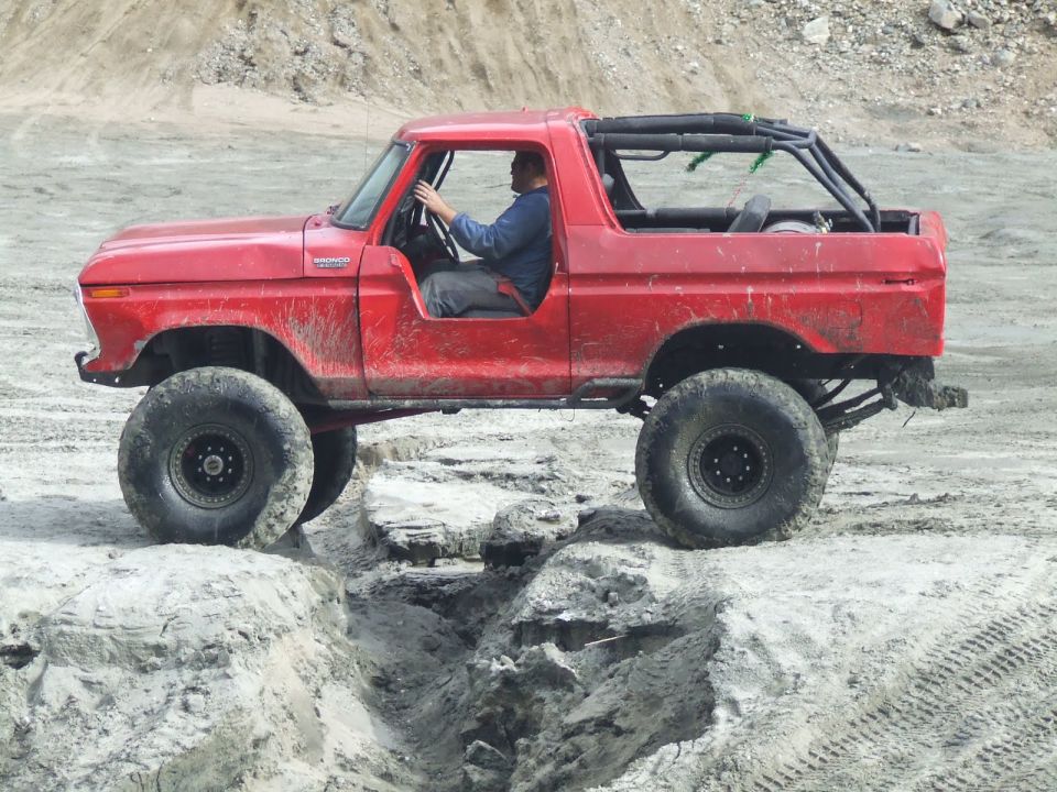 Red 1978 Ford Bronco off-roading on a dirt track