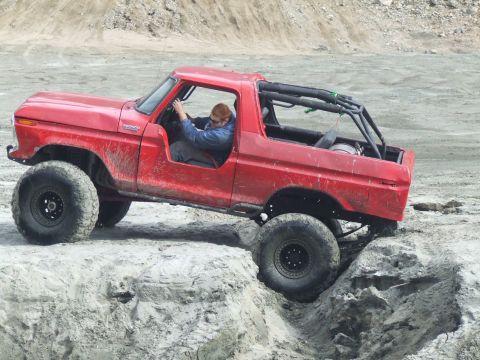 1978 Ford Bronco - A red 1978 Ford Bronco is shown off-roading over rocks.