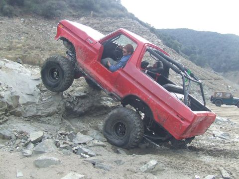 1978 Ford Bronco - Modified 1978 Ford Bronco navigating a steep, rocky trail with another Jeep visible in the distance.
