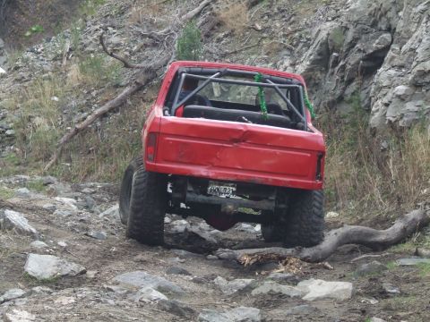 1978 Ford Bronco - Red 1978 Ford Bronco with roll cage navigating a rocky off-road trail.